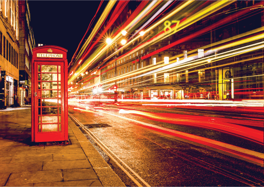 Road traffic in London with a telephone box, at night