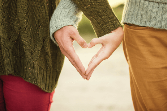 Couple linking arms making a heart with their hands, cohabitation